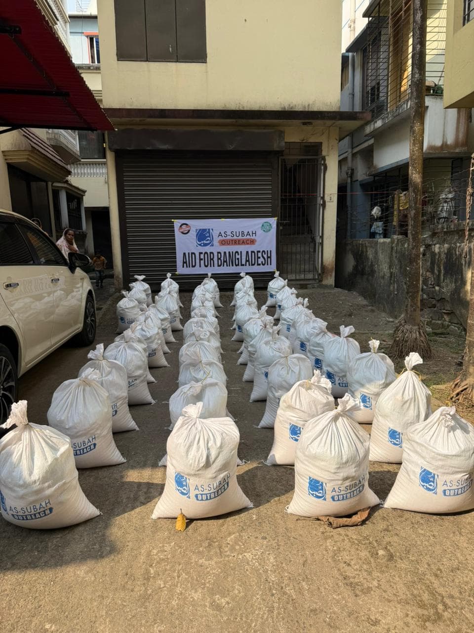 Aid sacks lined up at an As-Subah Outreach distribution for Bangladesh