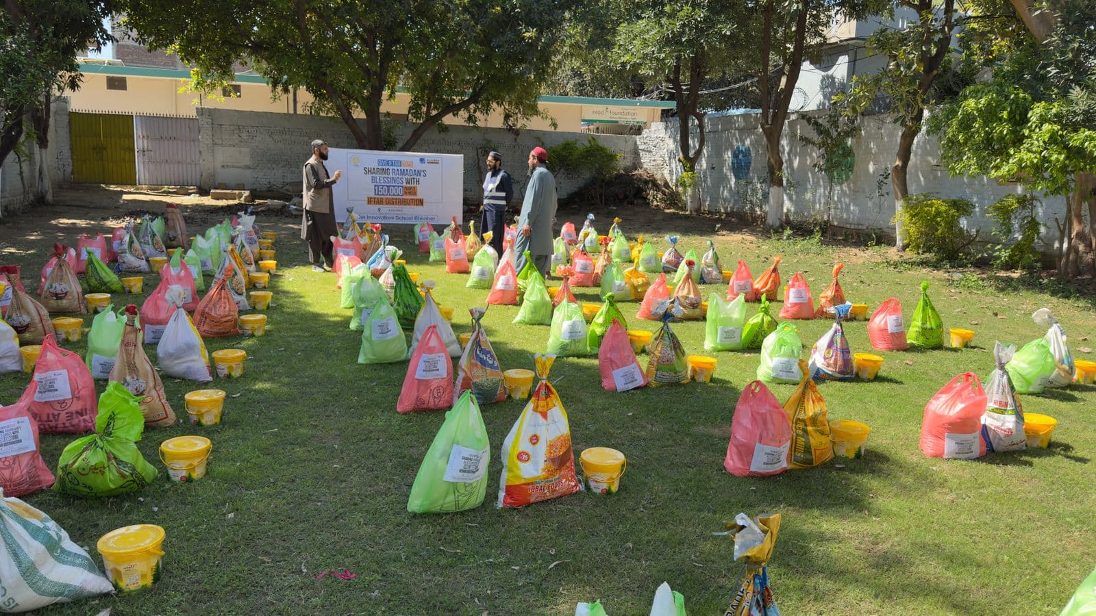 Outdoor food aid distribution: rows of supply packages and volunteers at an Iftar programme.